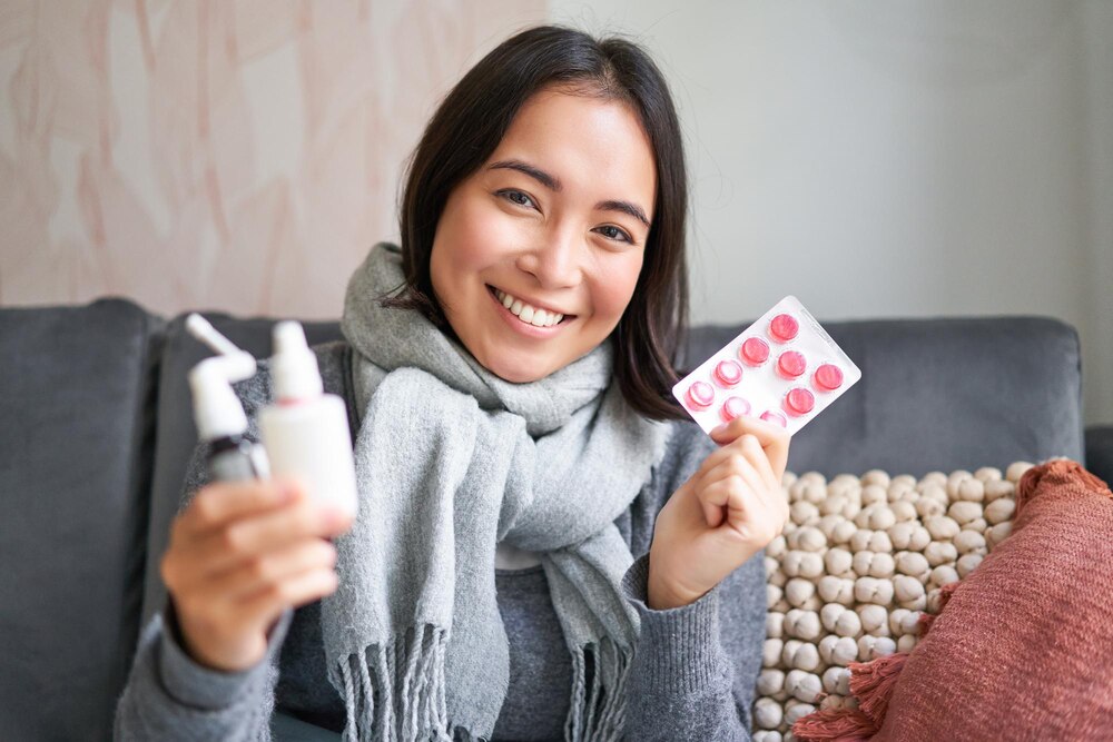Portrait of happy smiling asian girl showing medication sore throat spray and drugs from flu or cold