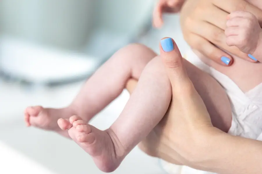 Newborn baby in mothers hands legs closeup
